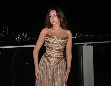 هنا الزاهد ترتدي فستانًا ذهبيًا لامعًا من تصميم إيلي صعب وتحمل جائزة "أفضل ممثلة" في حفل DIAFA بدبي.